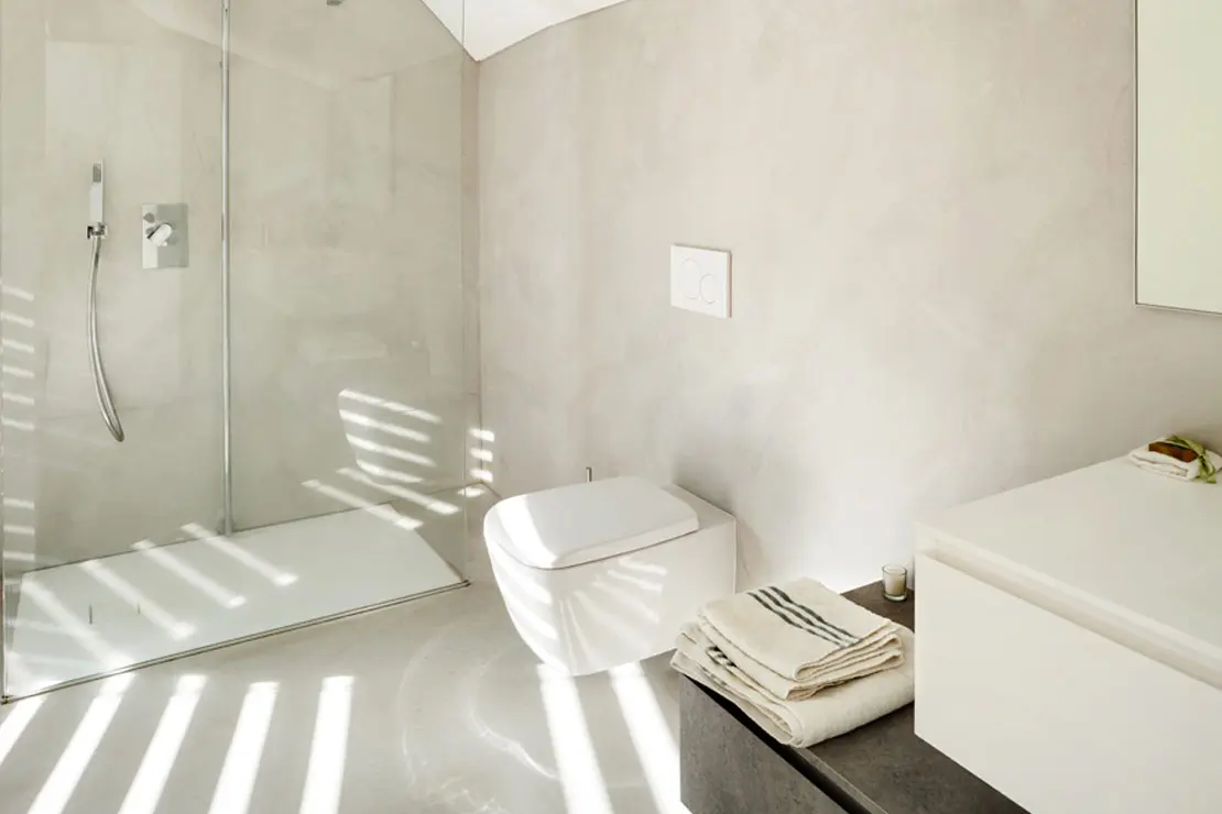 Baño con piso y muros de microcemento en tono suave